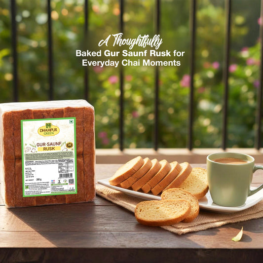 Dhamra Green Gur Saunf Rusk with a cup of tea on a wooden table outdoors.