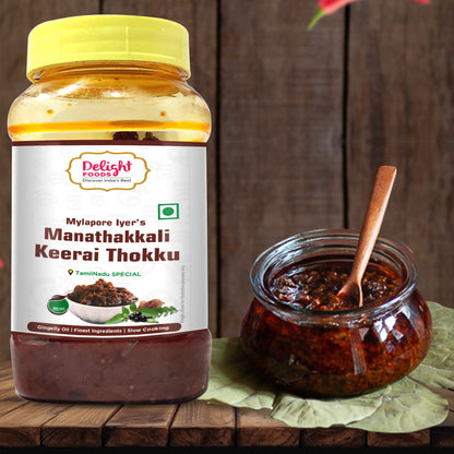 Jar of Manathakkali Keerai Thokku with a spoon on a wooden surface